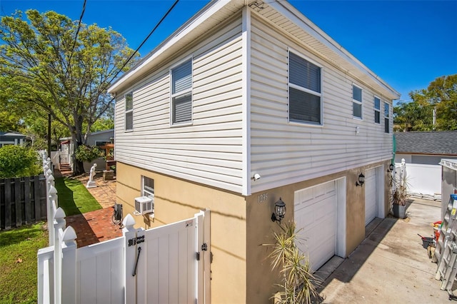 view of side of home featuring a fenced front yard, stucco siding, a garage, and a gate