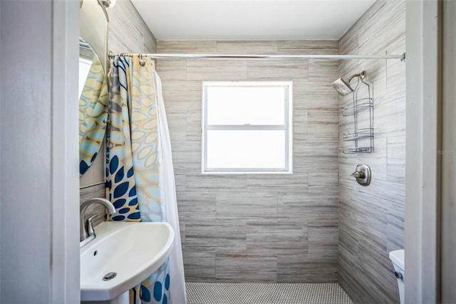 full bathroom featuring toilet, tiled shower, and a sink