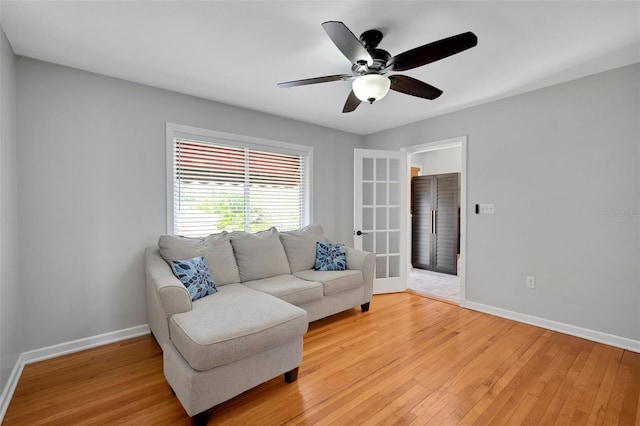 sitting room with a ceiling fan, light wood-type flooring, and baseboards