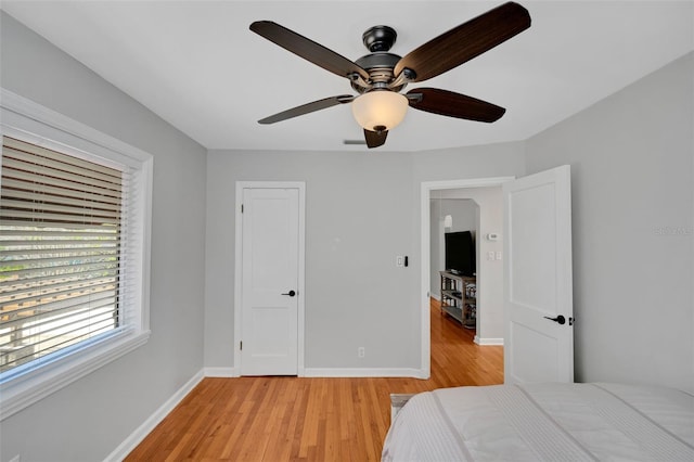 bedroom featuring baseboards, light wood-style floors, and ceiling fan