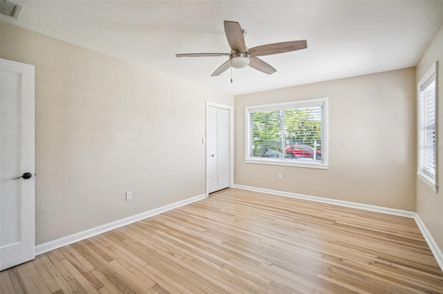 spare room featuring visible vents, baseboards, light wood-style floors, and a ceiling fan