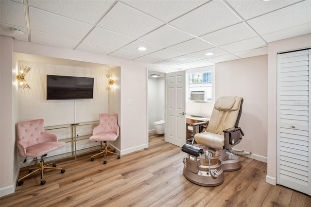 living area with a paneled ceiling, baseboards, and wood finished floors