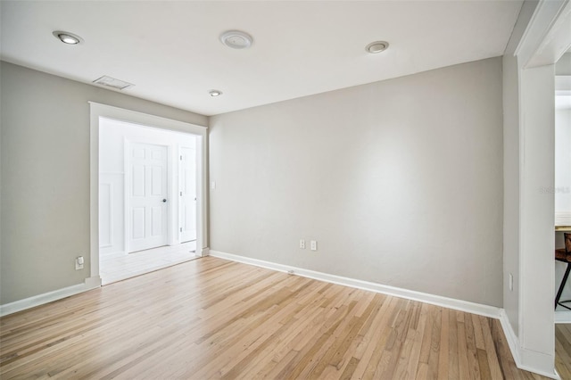 spare room with light wood-style flooring, visible vents, and baseboards