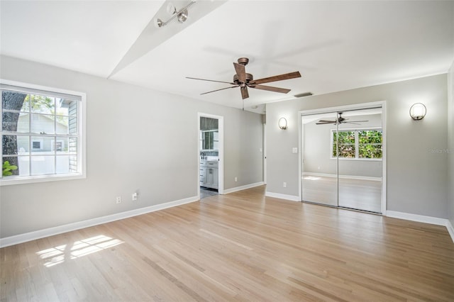 empty room featuring visible vents, light wood-style flooring, baseboards, and a ceiling fan