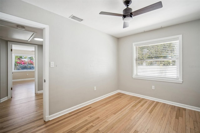 spare room featuring visible vents, ceiling fan, light wood-type flooring, and baseboards