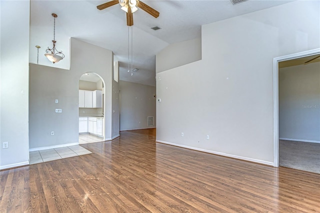 unfurnished room with baseboards, wood finished floors, arched walkways, and ceiling fan