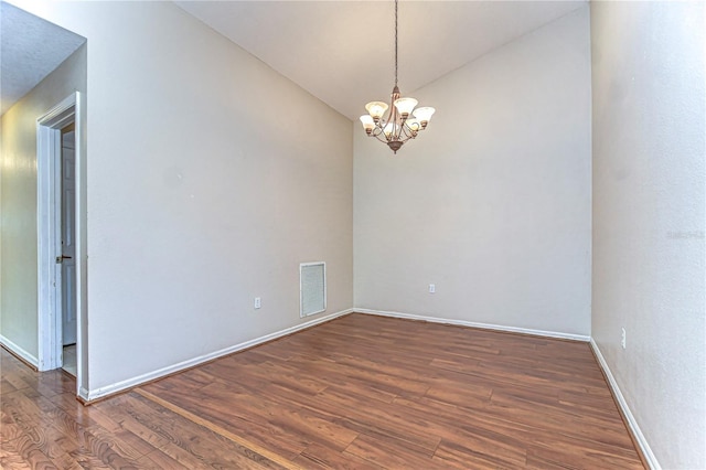 spare room with visible vents, dark wood-style floors, an inviting chandelier, baseboards, and vaulted ceiling