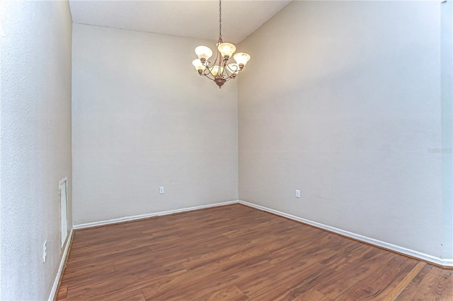 unfurnished room featuring visible vents, baseboards, an inviting chandelier, and wood finished floors