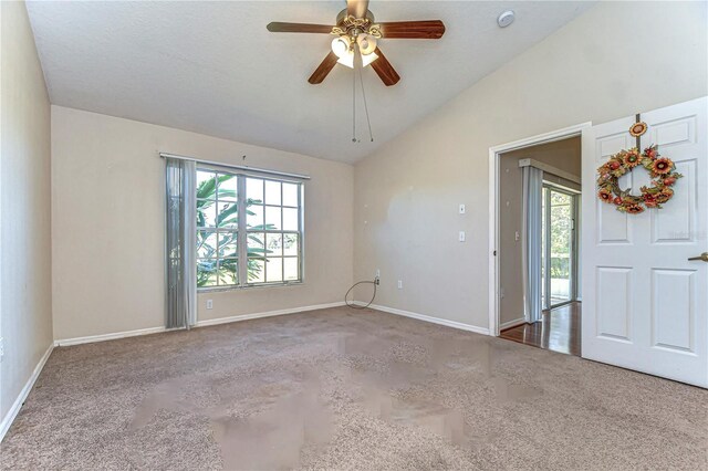 carpeted empty room with a wealth of natural light, baseboards, ceiling fan, and vaulted ceiling