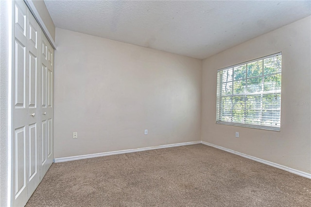 unfurnished bedroom with a closet, baseboards, a textured ceiling, and carpet flooring