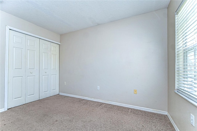 unfurnished bedroom featuring a closet, baseboards, a textured ceiling, and carpet