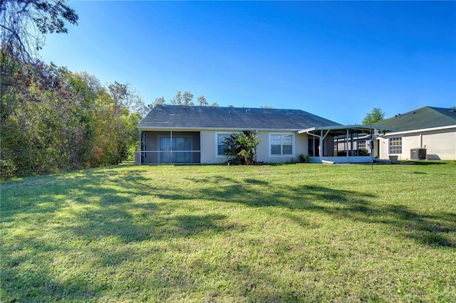 rear view of property featuring stucco siding, a lawn, central AC, and a sunroom