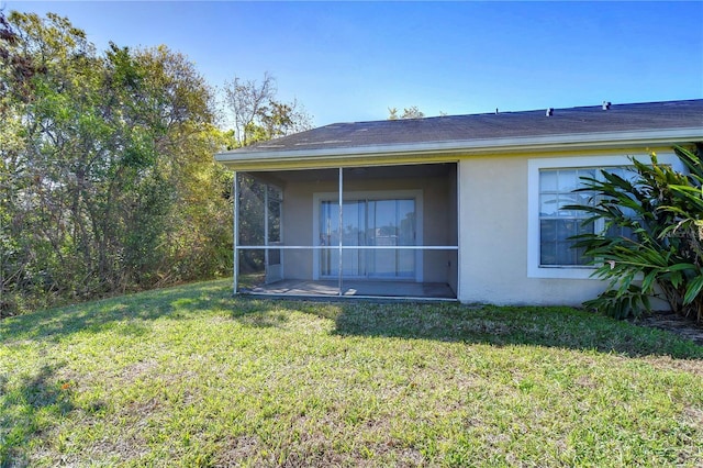 view of home's exterior with a yard, a sunroom, and stucco siding