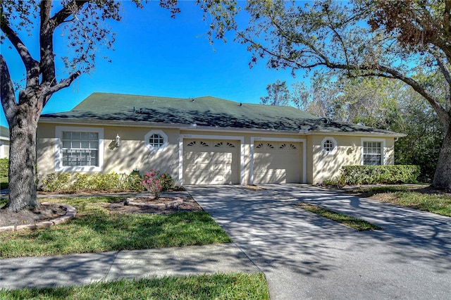 single story home with a garage, driveway, and stucco siding