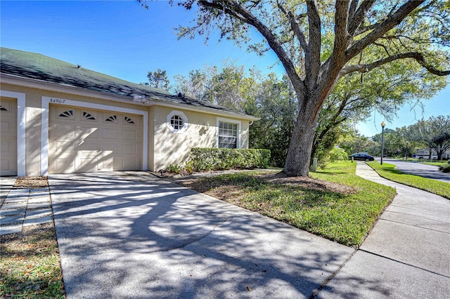 view of side of property with stucco siding, driveway, and an attached garage