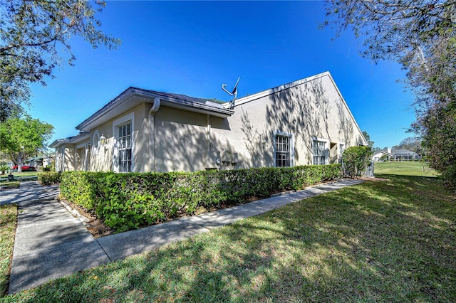 view of property exterior with stucco siding and a lawn