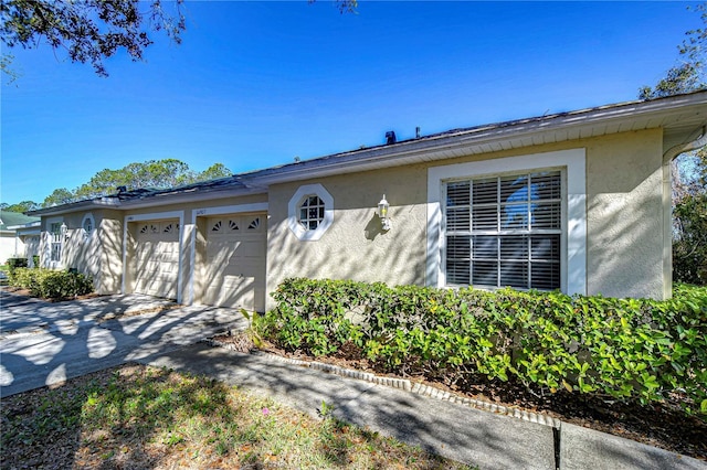 ranch-style house with an attached garage, driveway, and stucco siding