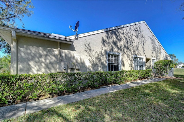 view of property exterior with stucco siding and a lawn