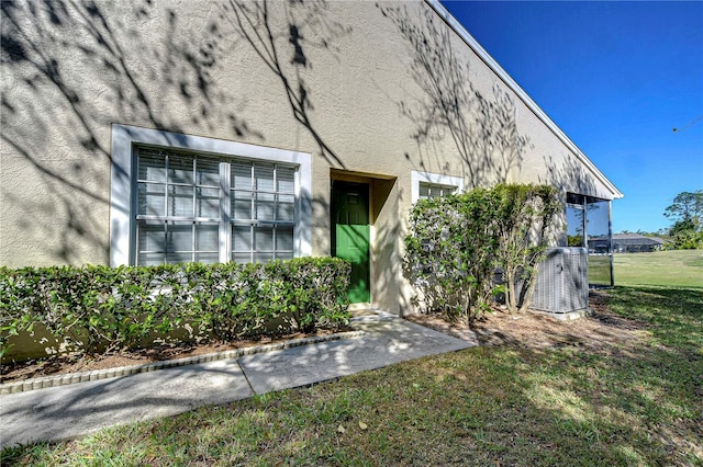 exterior space with a front lawn, central air condition unit, and stucco siding