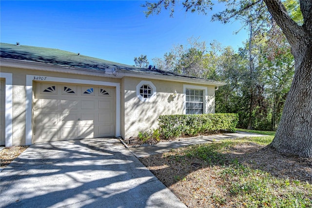 view of front of house with stucco siding, a garage, and driveway