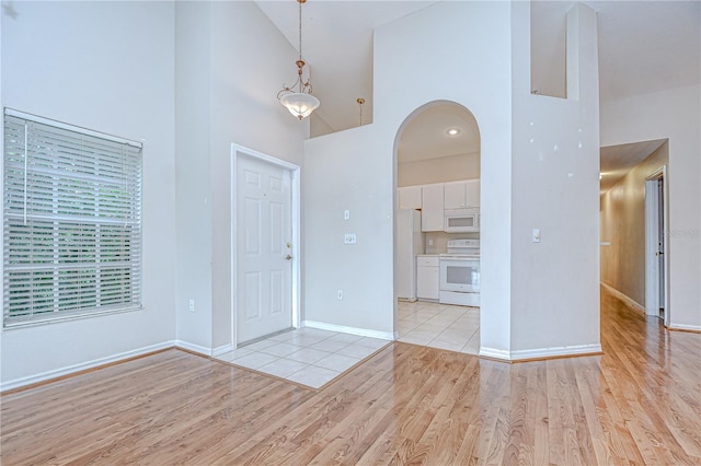 34907 Double Eagle Ct, Zephyrhills, FL 33541 - entryway with high vaulted ceiling, arched walkways, light wood finished floors, and baseboards