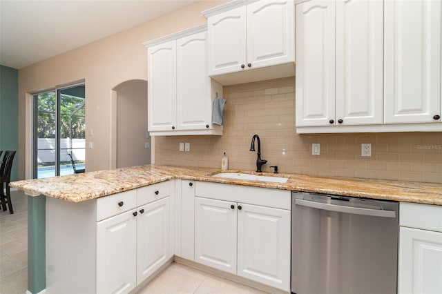 7581 Palmer Glen Cir, Sarasota, FL 34240 - kitchen with stainless steel dishwasher, a sink, tasteful backsplash, a peninsula, and white cabinets