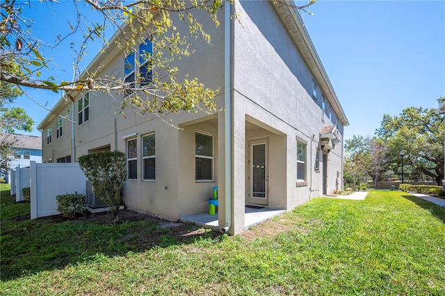 view of side of home featuring a yard, a patio, stucco siding, and fence