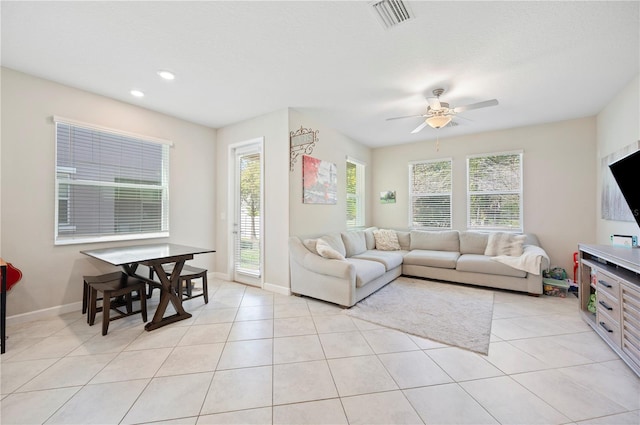 living area featuring light tile patterned flooring, visible vents, baseboards, and a ceiling fan