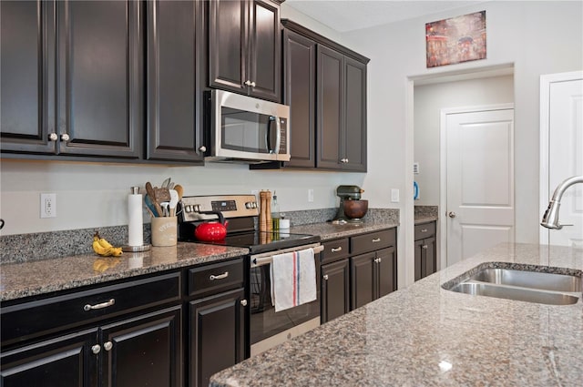 kitchen with dark stone countertops, appliances with stainless steel finishes, and a sink