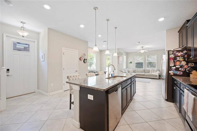 kitchen with a kitchen bar, light tile patterned floors, stainless steel appliances, and a sink