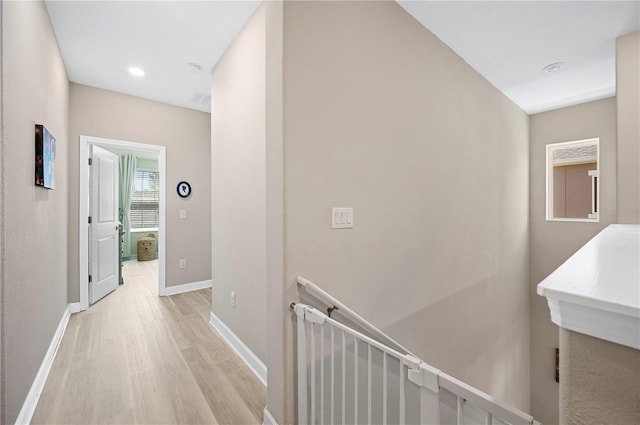 hall with recessed lighting, baseboards, an upstairs landing, and light wood-style floors