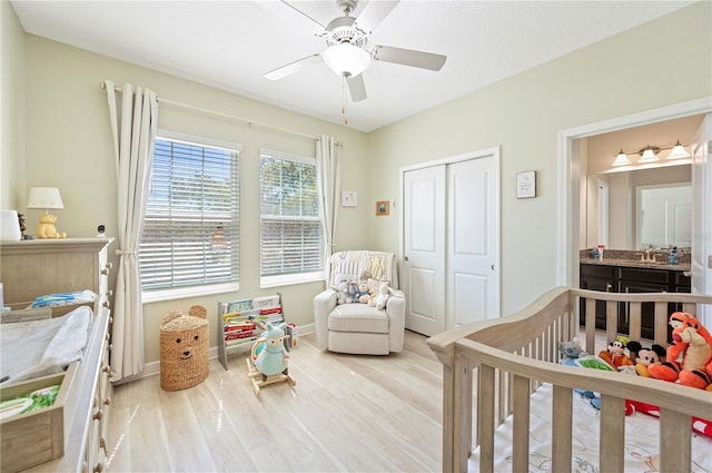 bedroom with a ceiling fan, a sink, wood finished floors, a closet, and baseboards