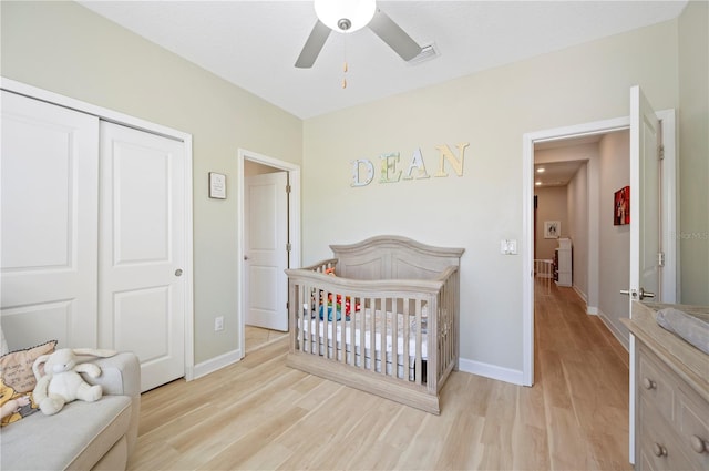 bedroom featuring light wood finished floors, visible vents, baseboards, and a closet