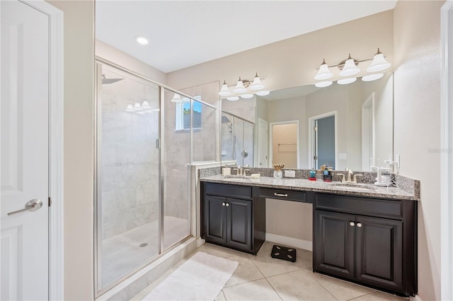 full bath with a sink, a stall shower, double vanity, and tile patterned floors