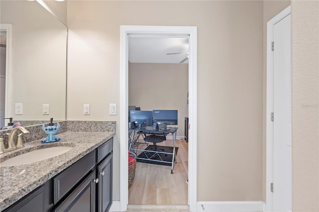 bathroom with ceiling fan, baseboards, wood finished floors, and vanity