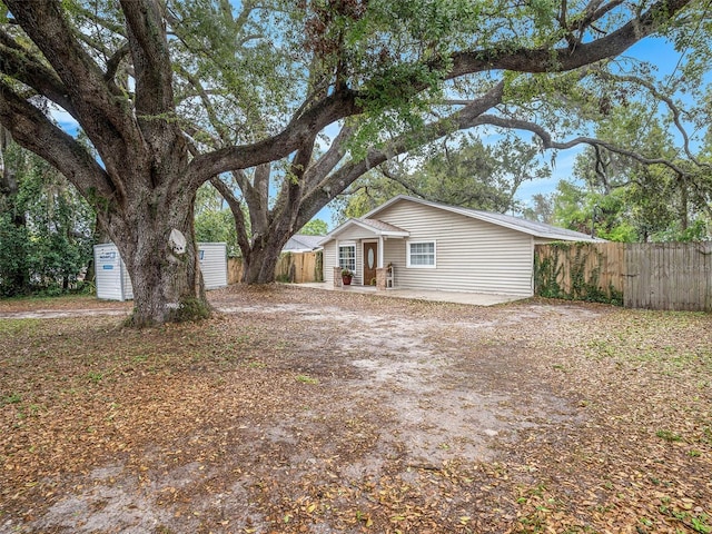 view of front of property with an outbuilding, a storage shed, and fence