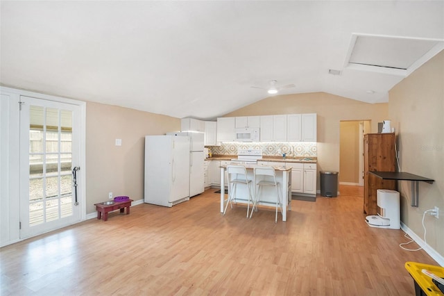 kitchen with light wood-type flooring, a kitchen bar, white cabinetry, white appliances, and decorative backsplash