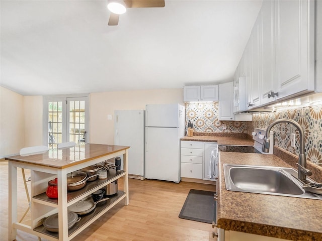 kitchen featuring tasteful backsplash, light wood-style flooring, freestanding refrigerator, and a sink