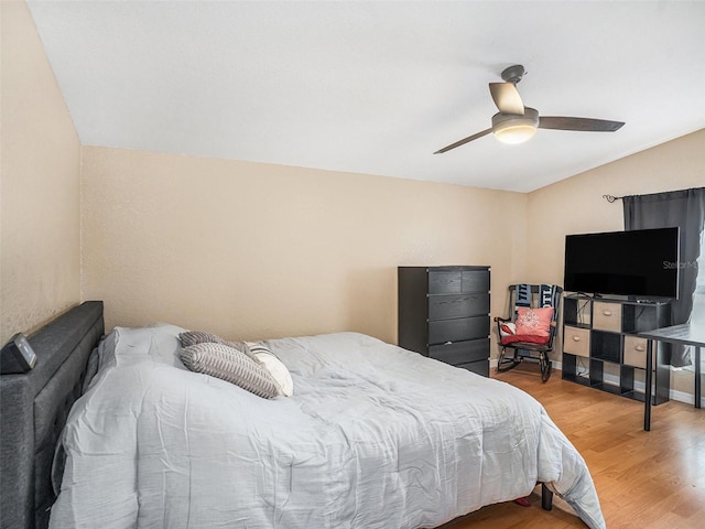 bedroom with baseboards, lofted ceiling, wood finished floors, and a ceiling fan