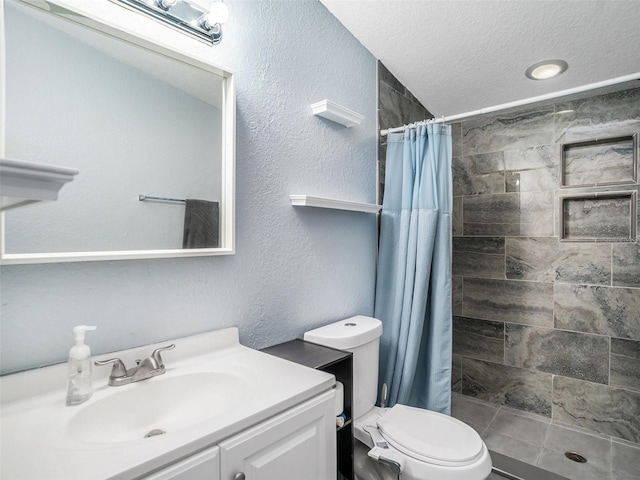 full bath featuring vanity, tiled shower, a textured ceiling, toilet, and a textured wall