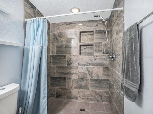 bathroom featuring toilet, a stall shower, and a textured ceiling