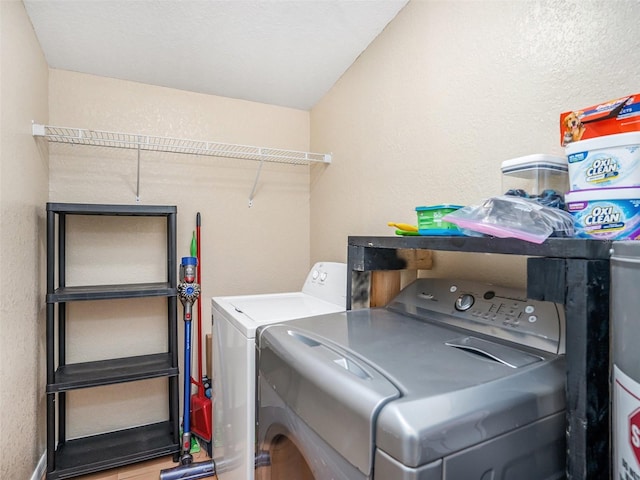 washroom with washer and dryer, laundry area, a textured wall, and baseboards