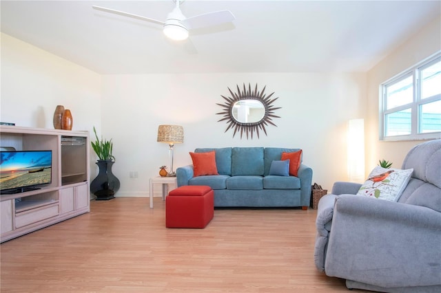 living room featuring baseboards, light wood-type flooring, and a ceiling fan