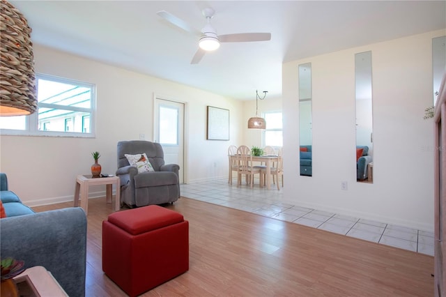 living area with tile patterned floors, baseboards, and ceiling fan