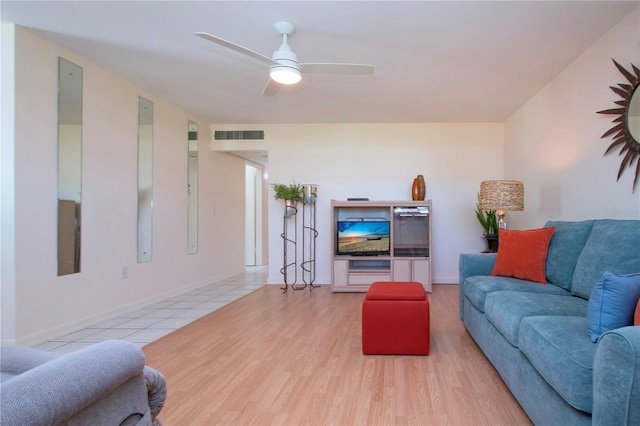 living area with baseboards, light wood-style floors, visible vents, and ceiling fan