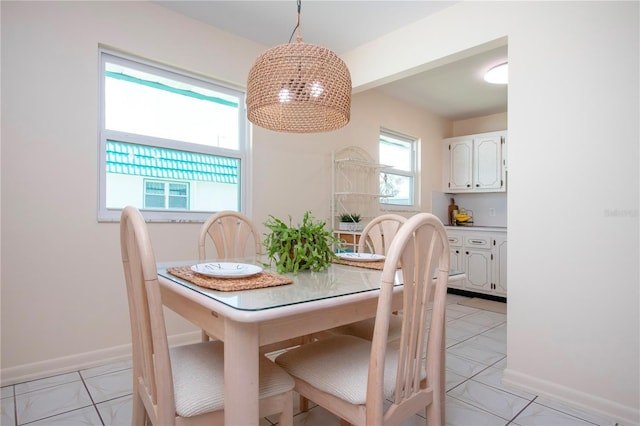 dining space featuring light tile patterned floors, baseboards, and a chandelier