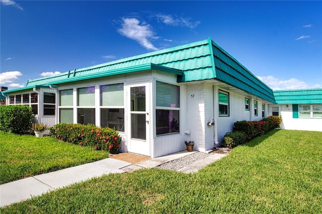 exterior space with a sunroom, a yard, and mansard roof