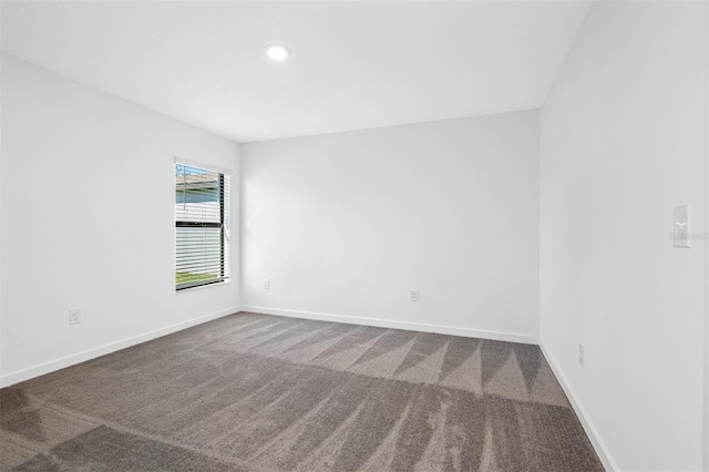 empty room with dark colored carpet and baseboards