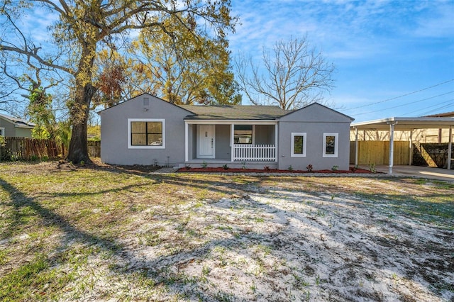 ranch-style home featuring a porch, stucco siding, fence, and a carport