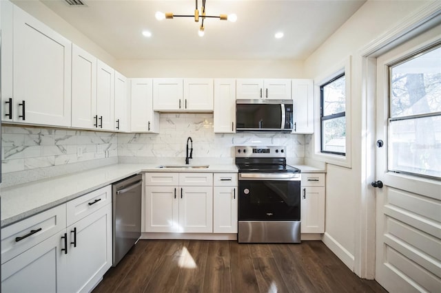 kitchen featuring a sink, decorative backsplash, appliances with stainless steel finishes, white cabinets, and dark wood-style flooring